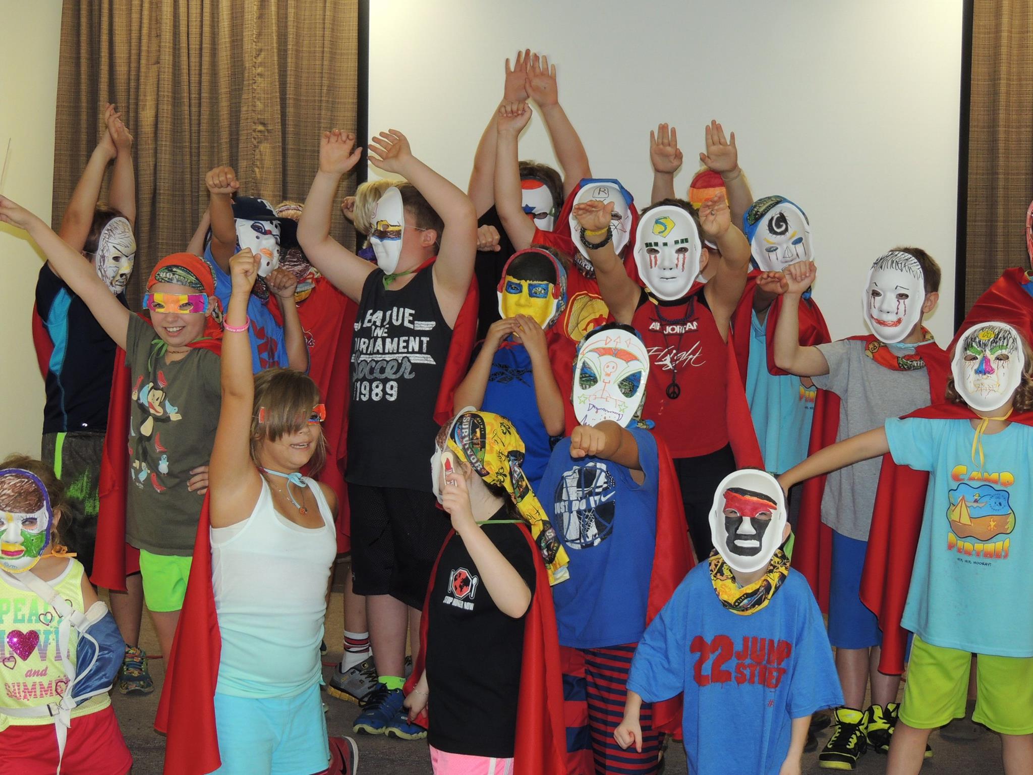 Camp Perthes kids in superhero masks and capes, arms raised