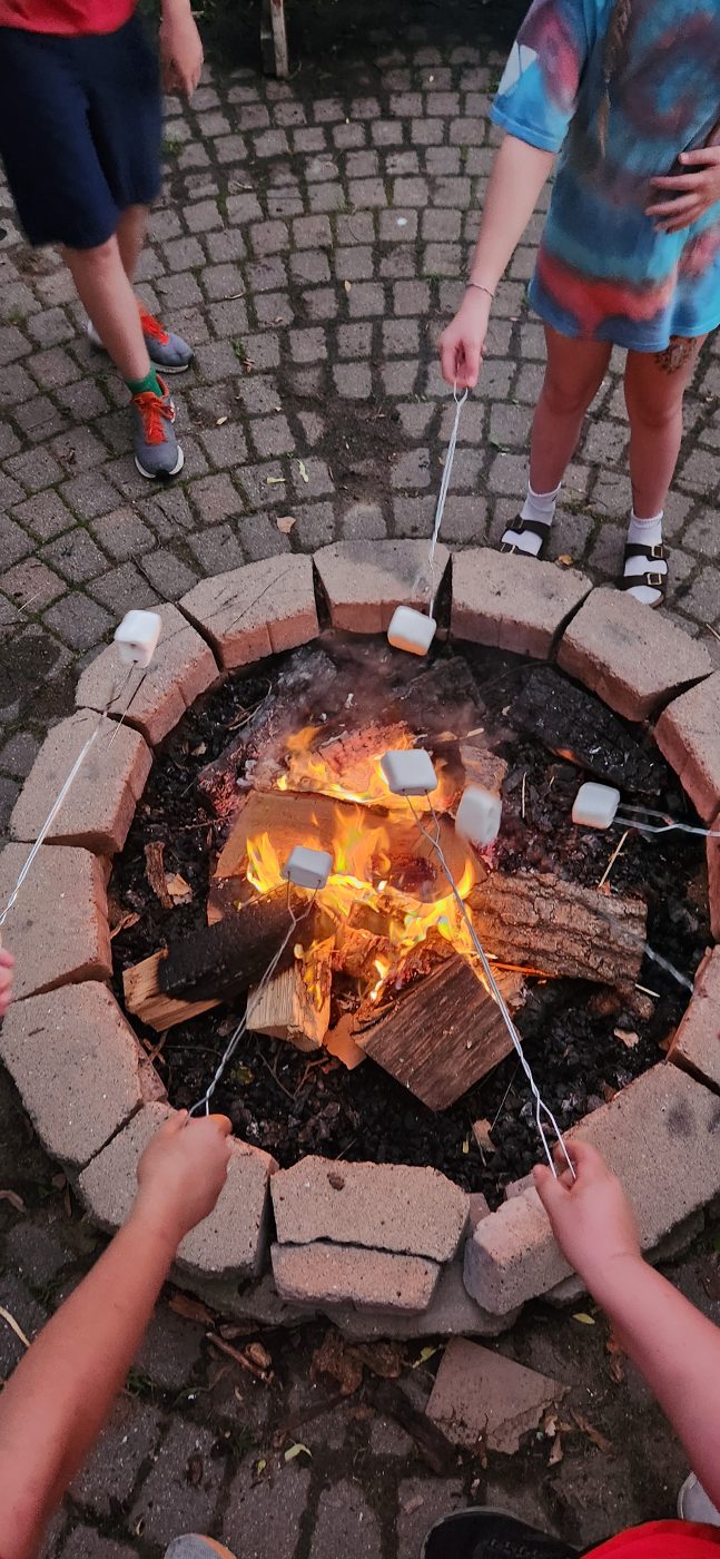Campers roasting marshmallows over a crackling campfire at Camp Perthes