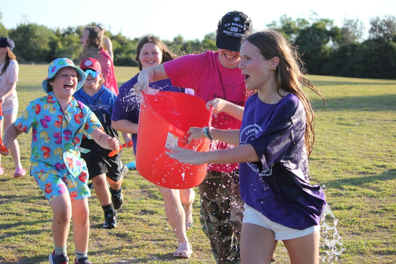Campers and a volunteer laughing during a bucket water fight at Camp Perthes