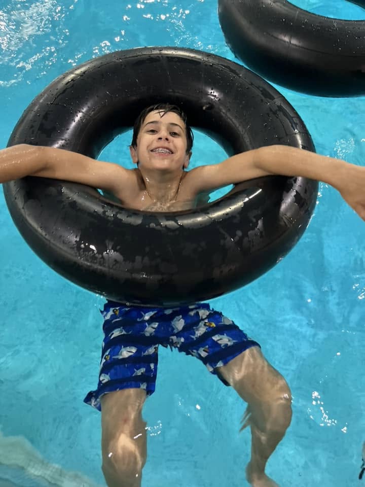 A camper floating in an inner tube in the pool