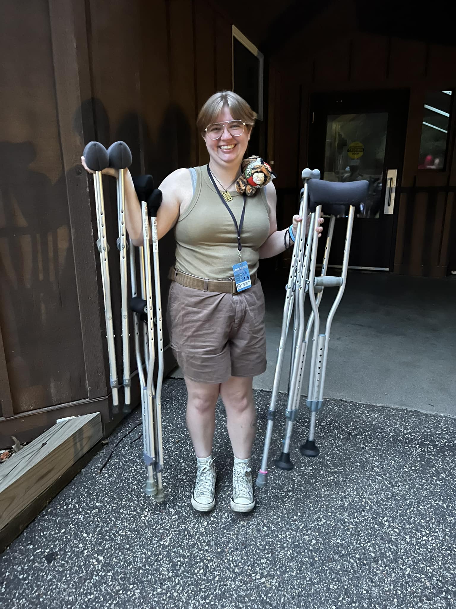 A grinning counselor holding campers' crutches at camp
