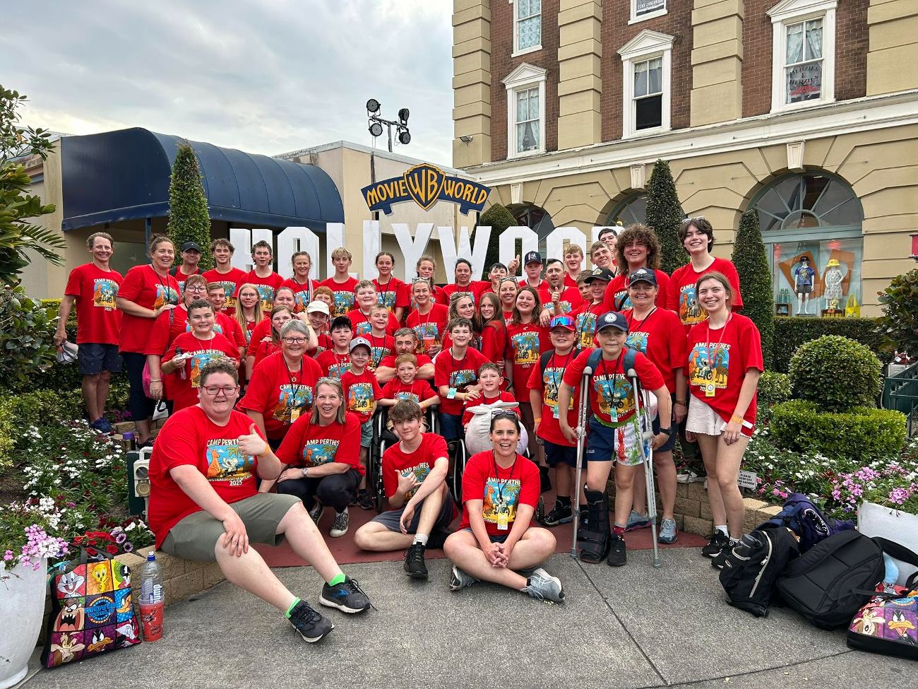 The whole Camp Perthes Australia group in red shirts posing together in front of the Movie World Hollywood sign