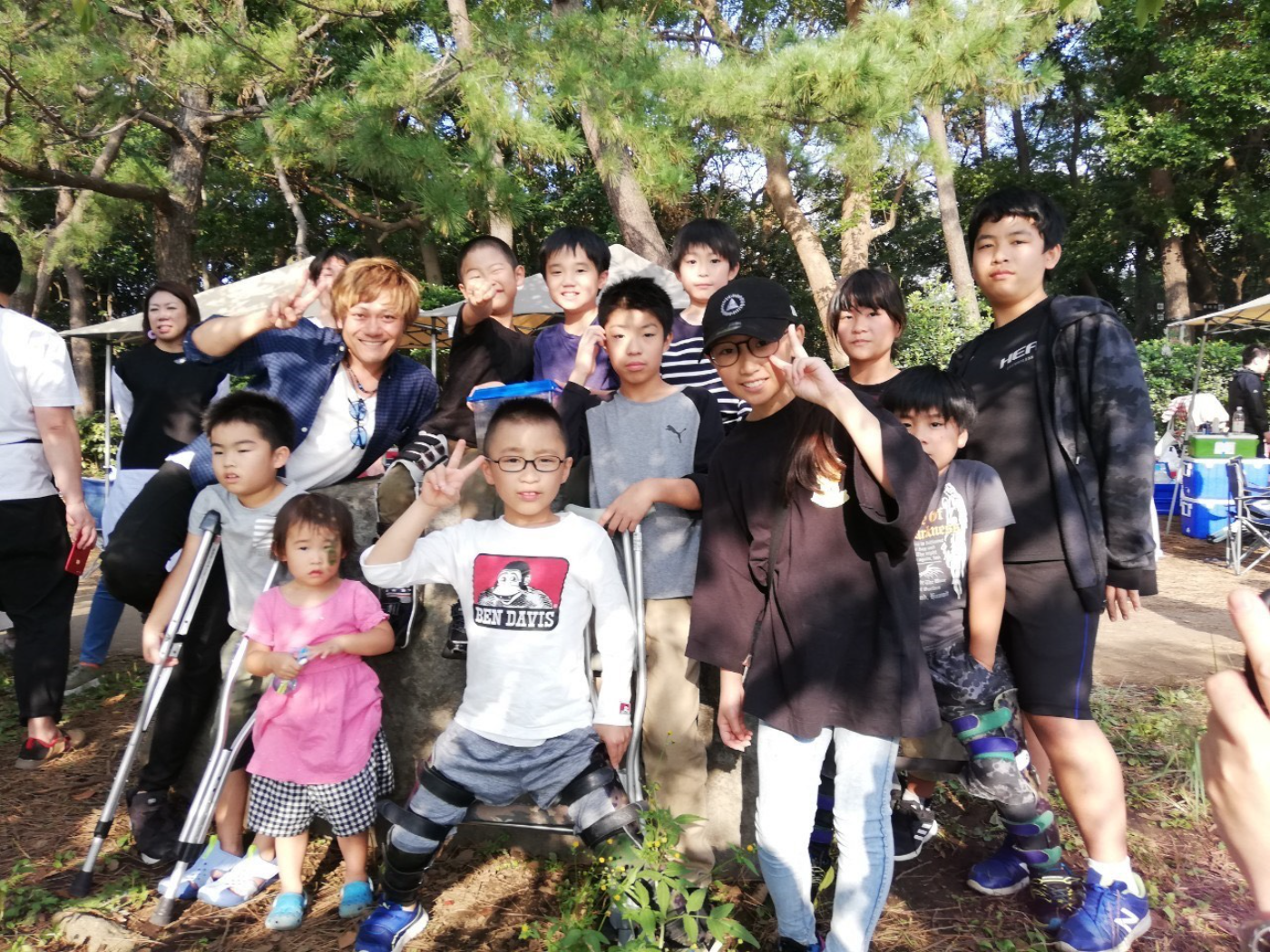 The Superview community of Perthes families gathered under tents at a park meetup in Tokyo, Japan, many children on crutches and in braces flashing peace signs