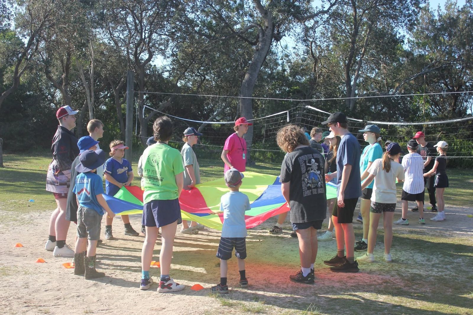 Camp Perthes volunteers and kids together holding a colorful parachute during a group game